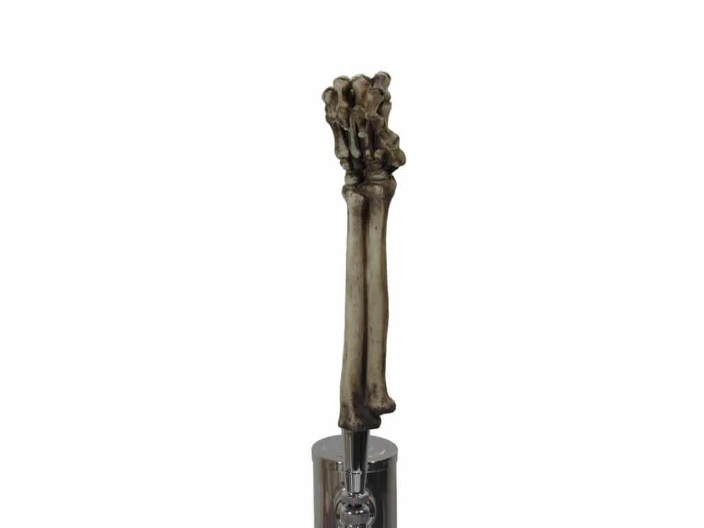 tan skeleton arm atop a beer tap handle