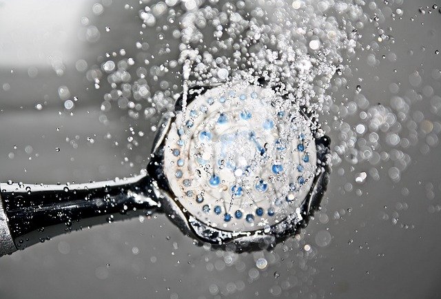 black shower head turned on upside down with water spraying out