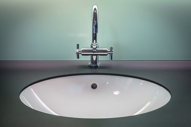 front view of a stainless steel bathroom sink with a black countertop