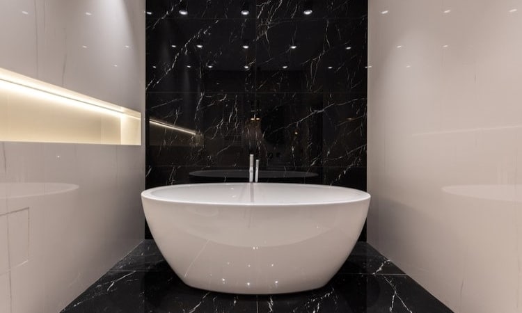 white stand alone bathtub bath tub in bathroom againest black floor and wall