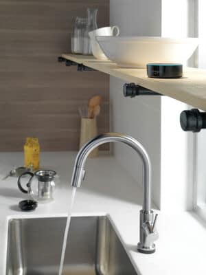 stainless steel kitchen sink faucet with water shooting out into sink