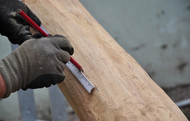 person measuring piece of wood