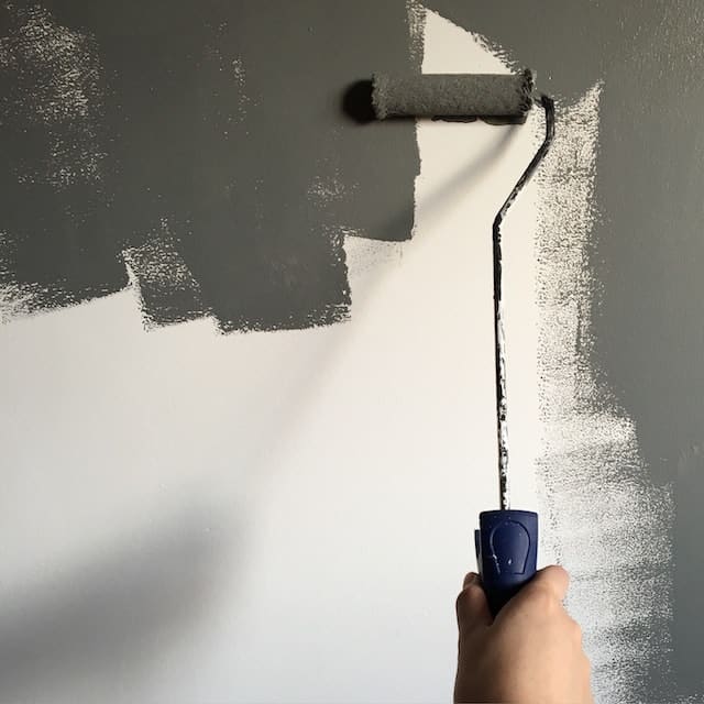 paint roller with gray paint on a white wall
